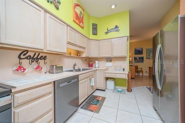 kitchen with sink, light tile patterned floors, stainless steel appliances, and light brown cabinets