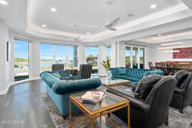 living room featuring a raised ceiling, plenty of natural light, dark hardwood / wood-style floors, and ceiling fan