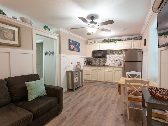 kitchen with crown molding, black appliances, light wood-type flooring, backsplash, and cream cabinetry