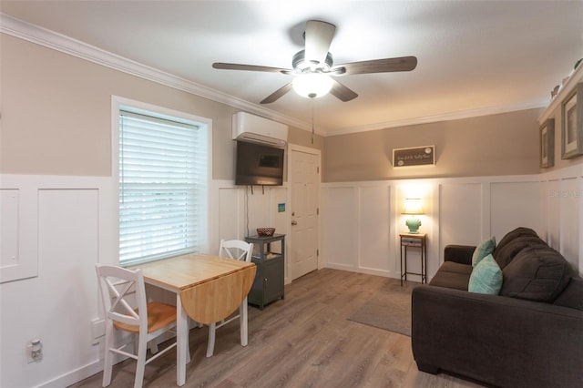 living room with ornamental molding, an AC wall unit, ceiling fan, and light wood-type flooring