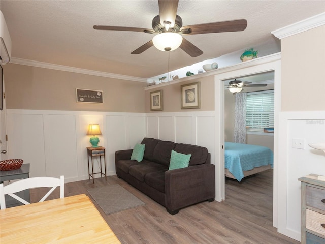 living room featuring crown molding, wood-type flooring, a textured ceiling, and ceiling fan