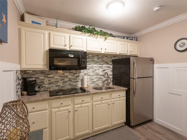 kitchen featuring sink, backsplash, cream cabinets, and black appliances