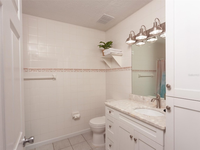 bathroom with tile patterned floors, toilet, tile walls, a textured ceiling, and vanity