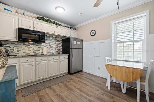 kitchen featuring light hardwood / wood-style flooring, ornamental molding, ceiling fan, decorative backsplash, and black appliances