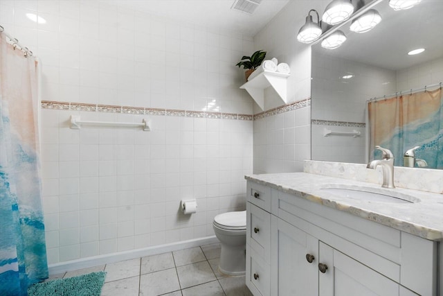 bathroom featuring walk in shower, toilet, tile walls, vanity, and tile patterned flooring