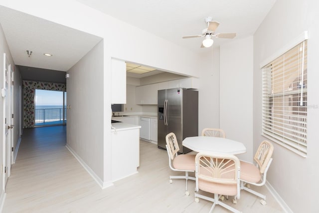 dining space featuring ceiling fan, light hardwood / wood-style floors, sink, and a textured ceiling