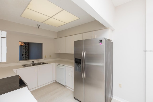 kitchen featuring white dishwasher, sink, white cabinetry, and stainless steel fridge