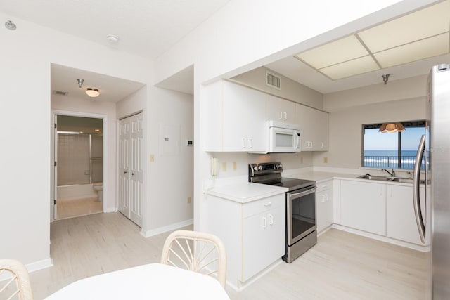 kitchen featuring sink, stainless steel appliances, light hardwood / wood-style floors, and white cabinets