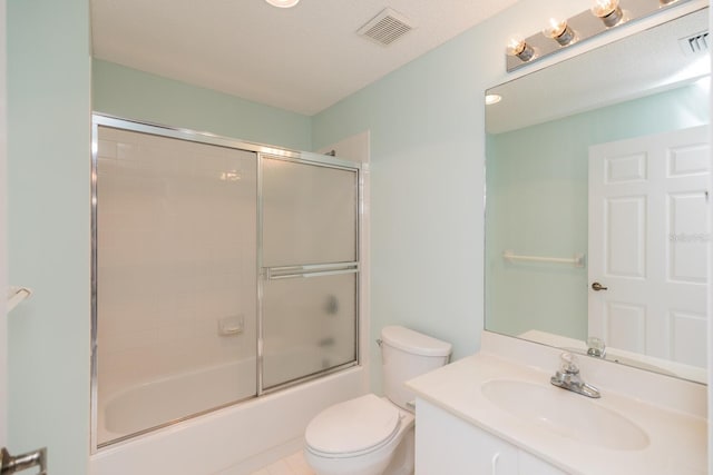 full bathroom with shower / bath combination with glass door, tile patterned flooring, vanity, toilet, and a textured ceiling