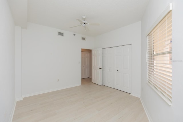 unfurnished bedroom with a textured ceiling, light hardwood / wood-style flooring, a closet, and ceiling fan