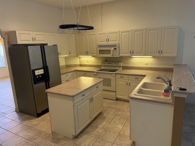 kitchen featuring sink, white appliances, white cabinetry, a center island, and kitchen peninsula