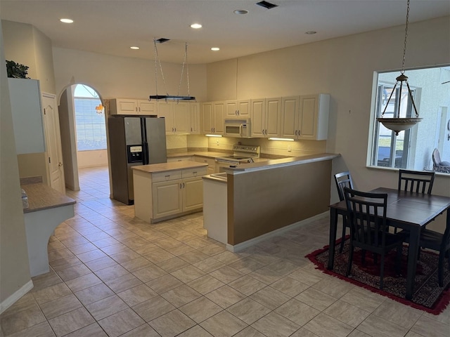 kitchen featuring stainless steel range with electric stovetop, decorative light fixtures, a center island, refrigerator with ice dispenser, and white cabinets