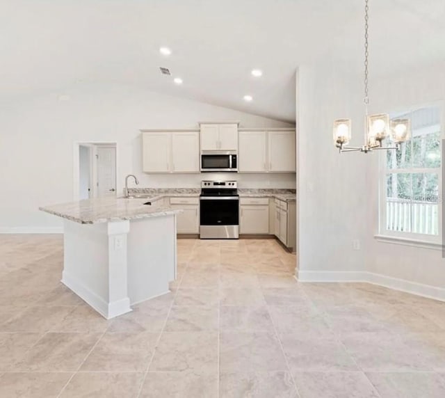 kitchen featuring white cabinets, appliances with stainless steel finishes, light stone counters, decorative light fixtures, and a sink