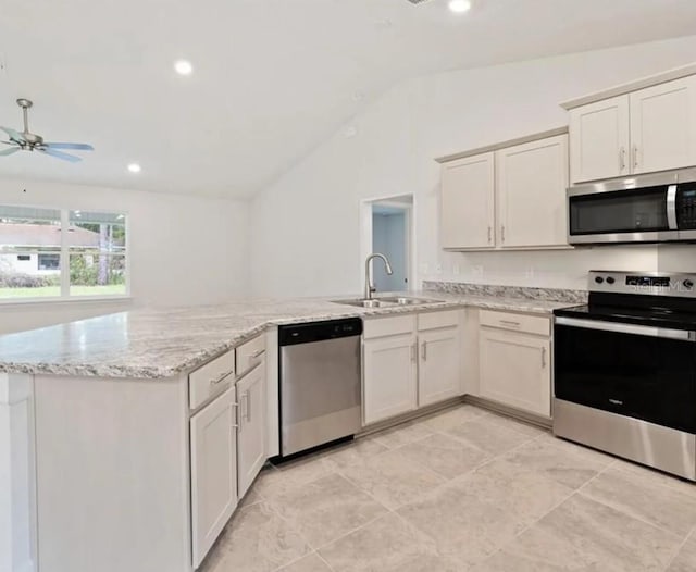 kitchen featuring a peninsula, appliances with stainless steel finishes, a sink, and light stone counters