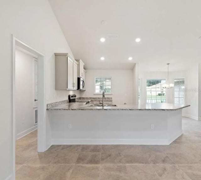 kitchen with recessed lighting, hanging light fixtures, appliances with stainless steel finishes, a sink, and a peninsula