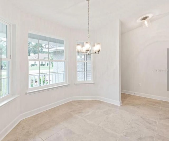 empty room with baseboards and a chandelier