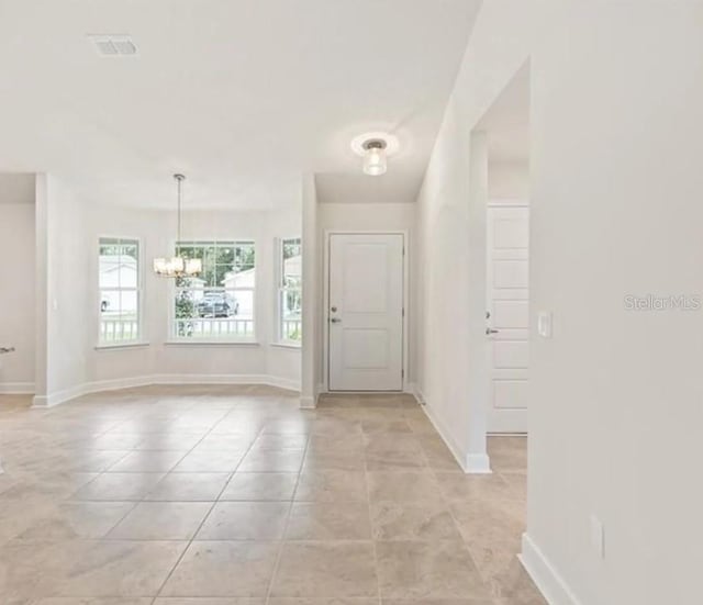 entrance foyer featuring light tile patterned flooring, a chandelier, visible vents, and baseboards