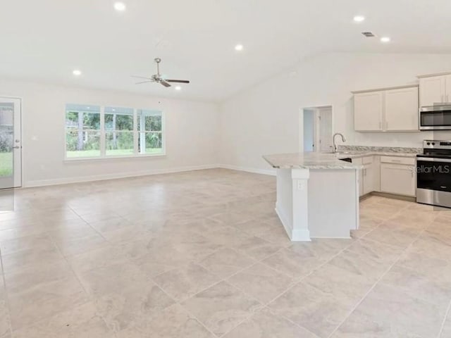 kitchen with lofted ceiling, a peninsula, open floor plan, and appliances with stainless steel finishes