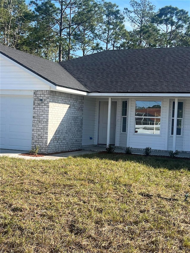 ranch-style house featuring a garage, brick siding, a front yard, and a shingled roof