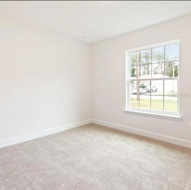 unfurnished room featuring baseboards, light colored carpet, and a healthy amount of sunlight