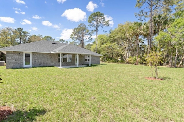 back of house with central AC, a yard, a shingled roof, brick siding, and a patio area