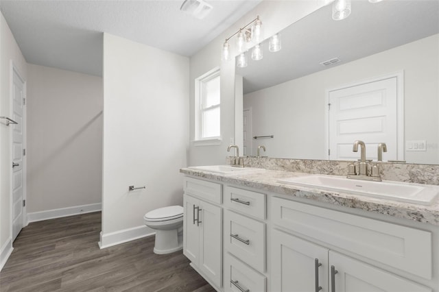 13 Primrose Ln, Palm Coast, FL 32164 - bathroom with double vanity, wood finished floors, toilet, and baseboards