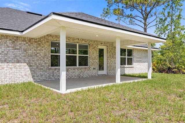 13 Primrose Ln, Palm Coast, FL 32164 - rear view of property featuring brick siding, roof with shingles, a yard, and a patio