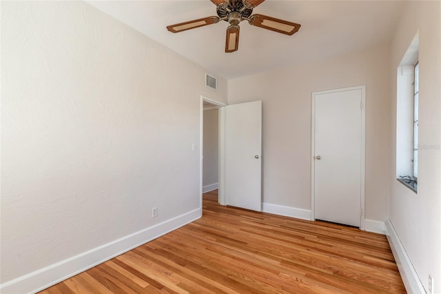 unfurnished bedroom with a baseboard radiator, ceiling fan, and light hardwood / wood-style floors