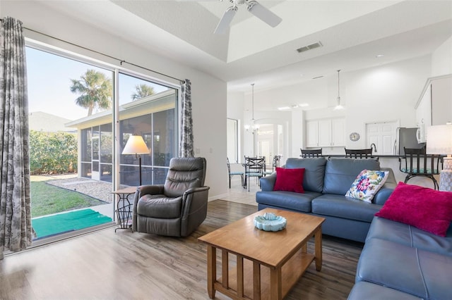 living room with ceiling fan with notable chandelier and hardwood / wood-style floors