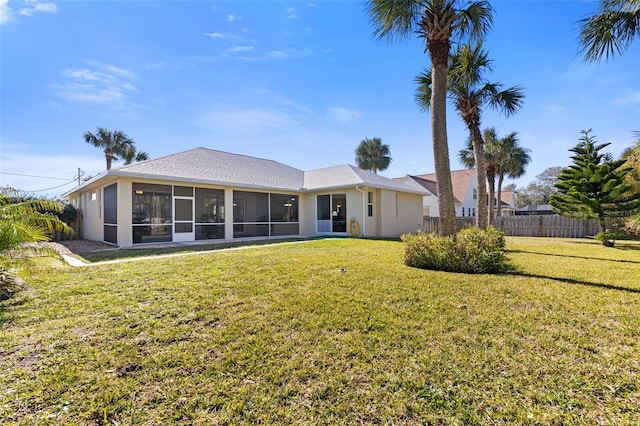 rear view of house featuring a sunroom and a lawn