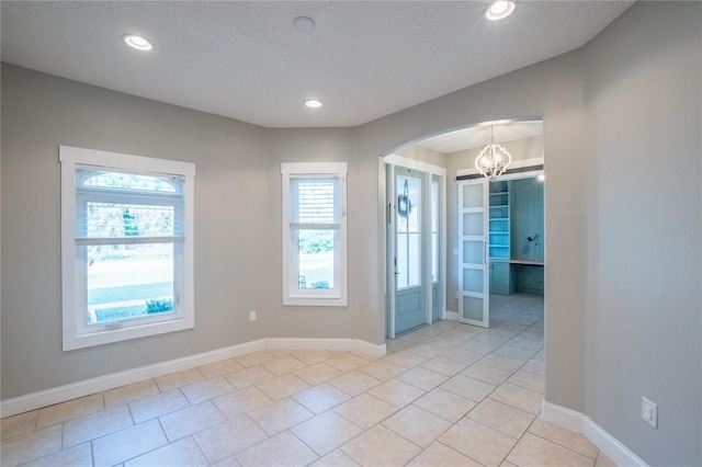 tiled empty room with a chandelier