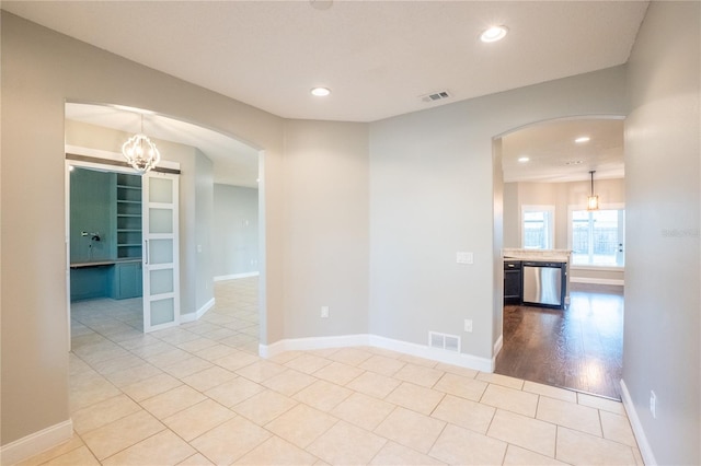 unfurnished room with a notable chandelier and light tile patterned floors