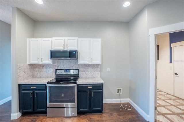 kitchen with dark hardwood / wood-style floors, tasteful backsplash, white cabinetry, stainless steel appliances, and a textured ceiling