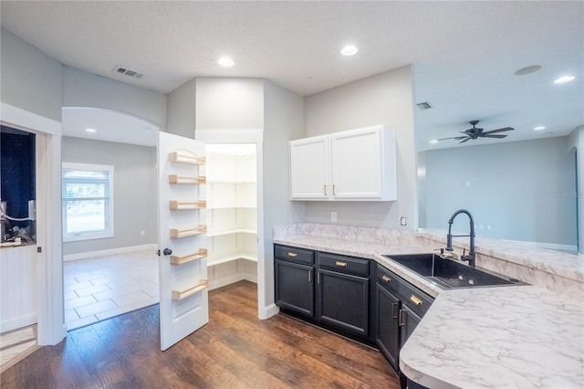 kitchen with sink, dark wood-type flooring, ceiling fan, white cabinetry, and kitchen peninsula