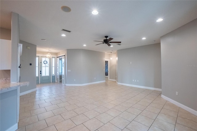 spare room featuring ceiling fan with notable chandelier and light tile patterned flooring