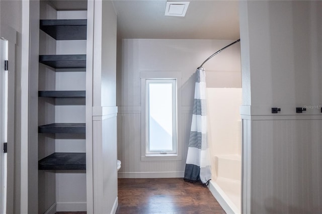 bathroom with hardwood / wood-style floors, built in shelves, curtained shower, and toilet