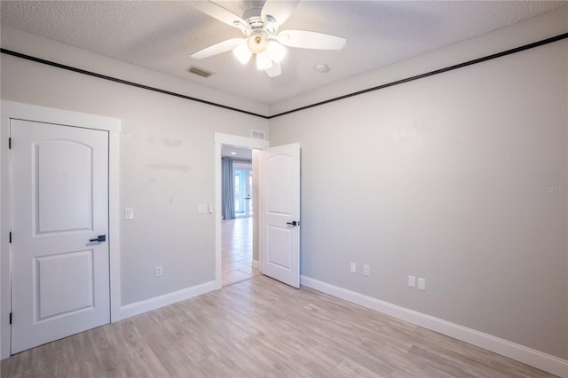 unfurnished bedroom with ceiling fan, a textured ceiling, and light wood-type flooring