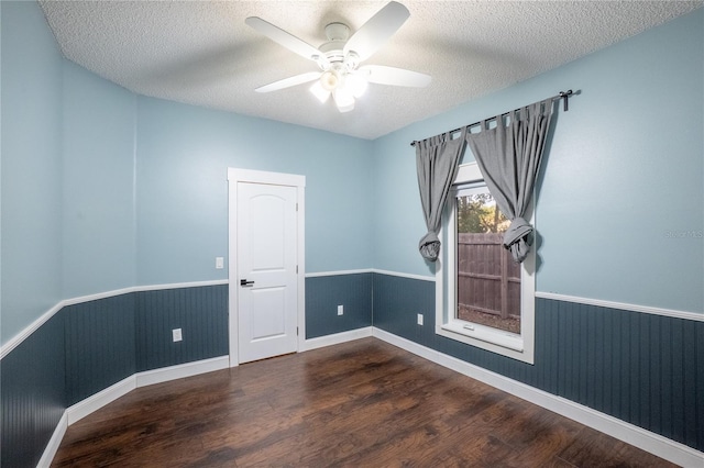 spare room featuring ceiling fan, dark wood-type flooring, and a textured ceiling