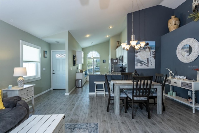 dining area with lofted ceiling, a notable chandelier, and light hardwood / wood-style floors