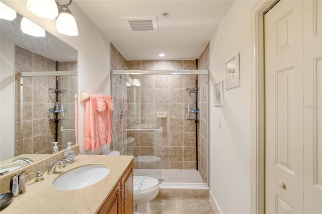 bathroom with vanity, tile patterned floors, a shower with door, and toilet