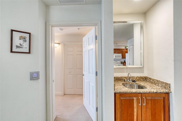 hall featuring sink and light carpet