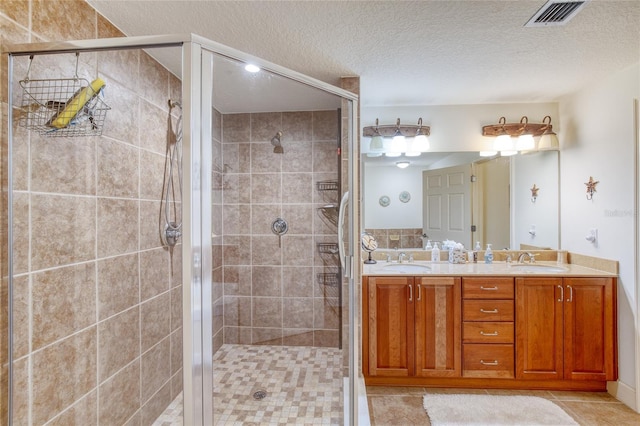 bathroom with vanity, a shower with shower door, tile patterned flooring, and a textured ceiling