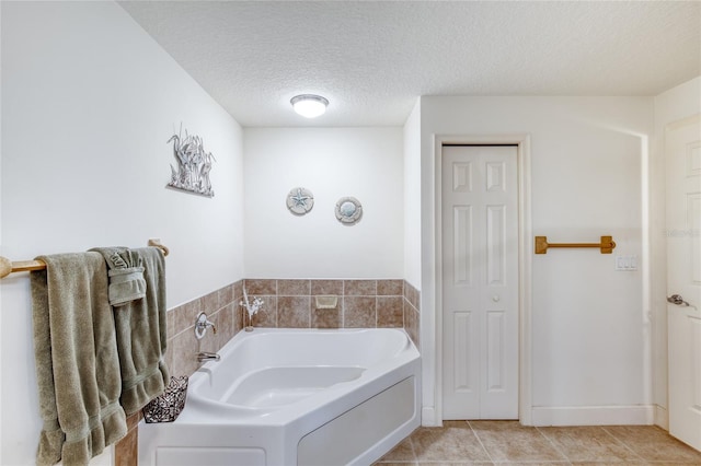 bathroom with tile patterned floors, a bathing tub, and a textured ceiling