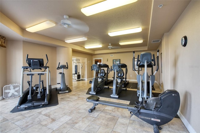 exercise room with a tray ceiling and a textured ceiling