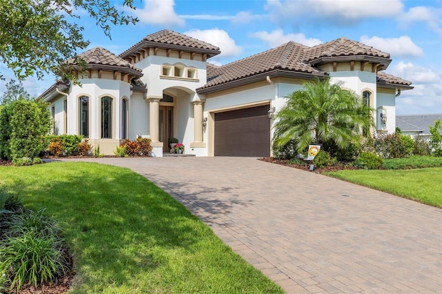 mediterranean / spanish-style home featuring a garage and a front yard