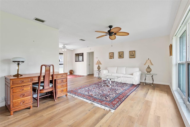 living area featuring light wood-type flooring, visible vents, ceiling fan, and baseboards