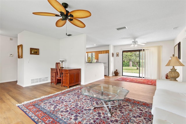 living room featuring baseboards, visible vents, and wood finished floors