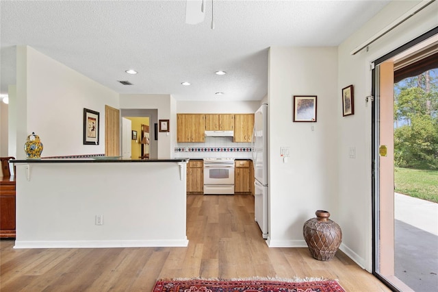 kitchen featuring white appliances, tasteful backsplash, visible vents, light wood-style floors, and under cabinet range hood