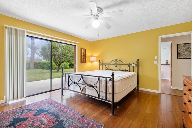 bedroom with access to outside, wood-type flooring, and a textured ceiling