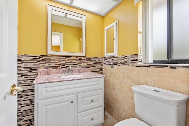 half bath with tile walls, vanity, and toilet